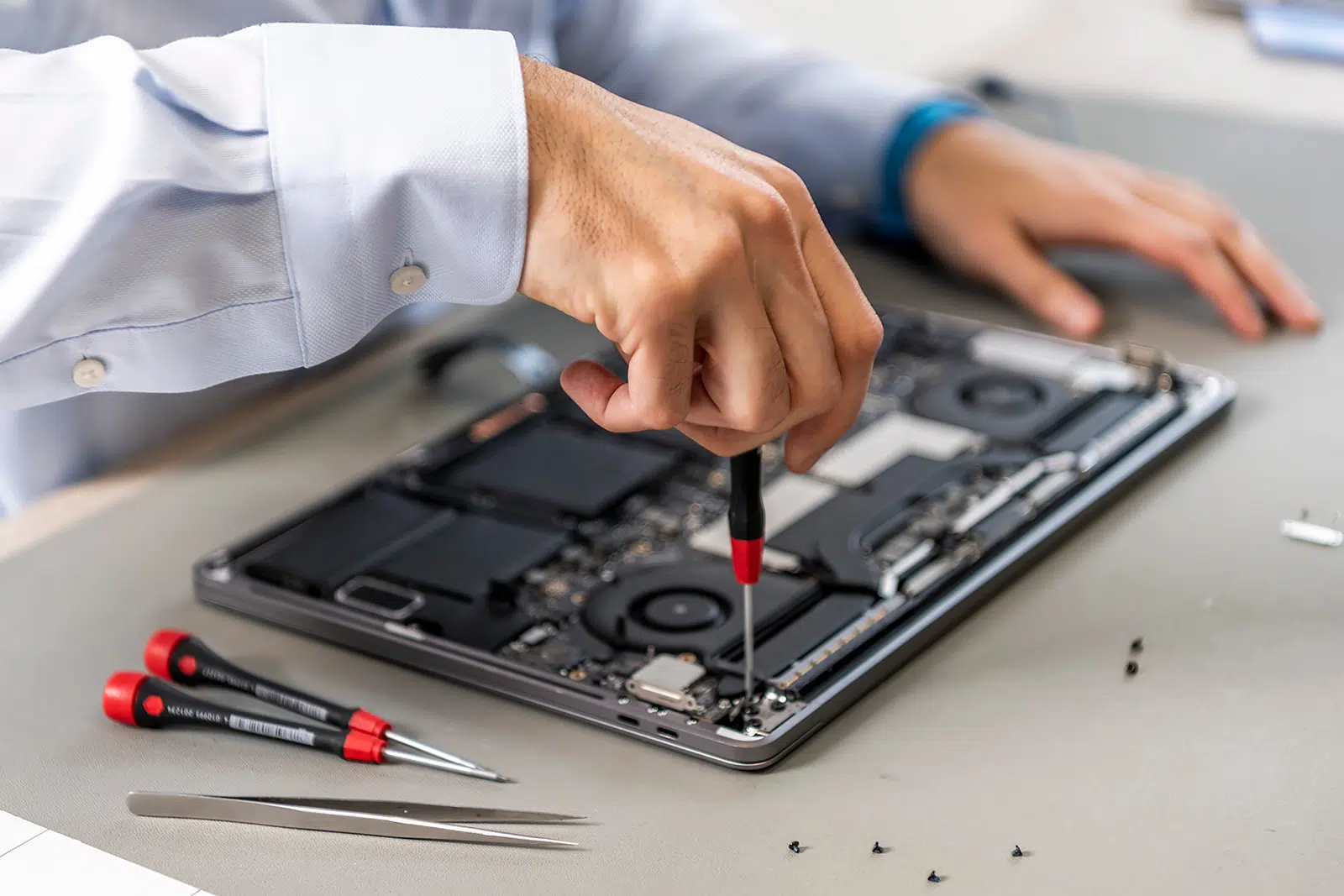Technician carefully inspecting a laptop motherboard